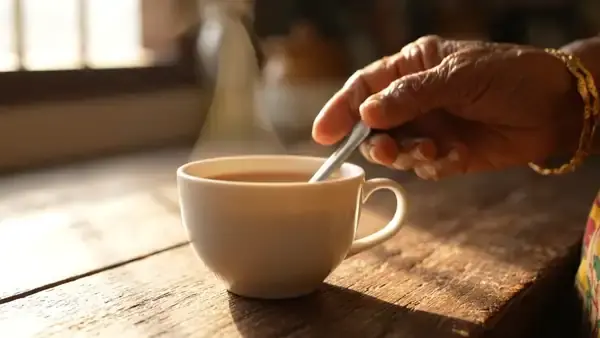 A spoon slowly stirring a cup of hot tea as steam rises in morning light